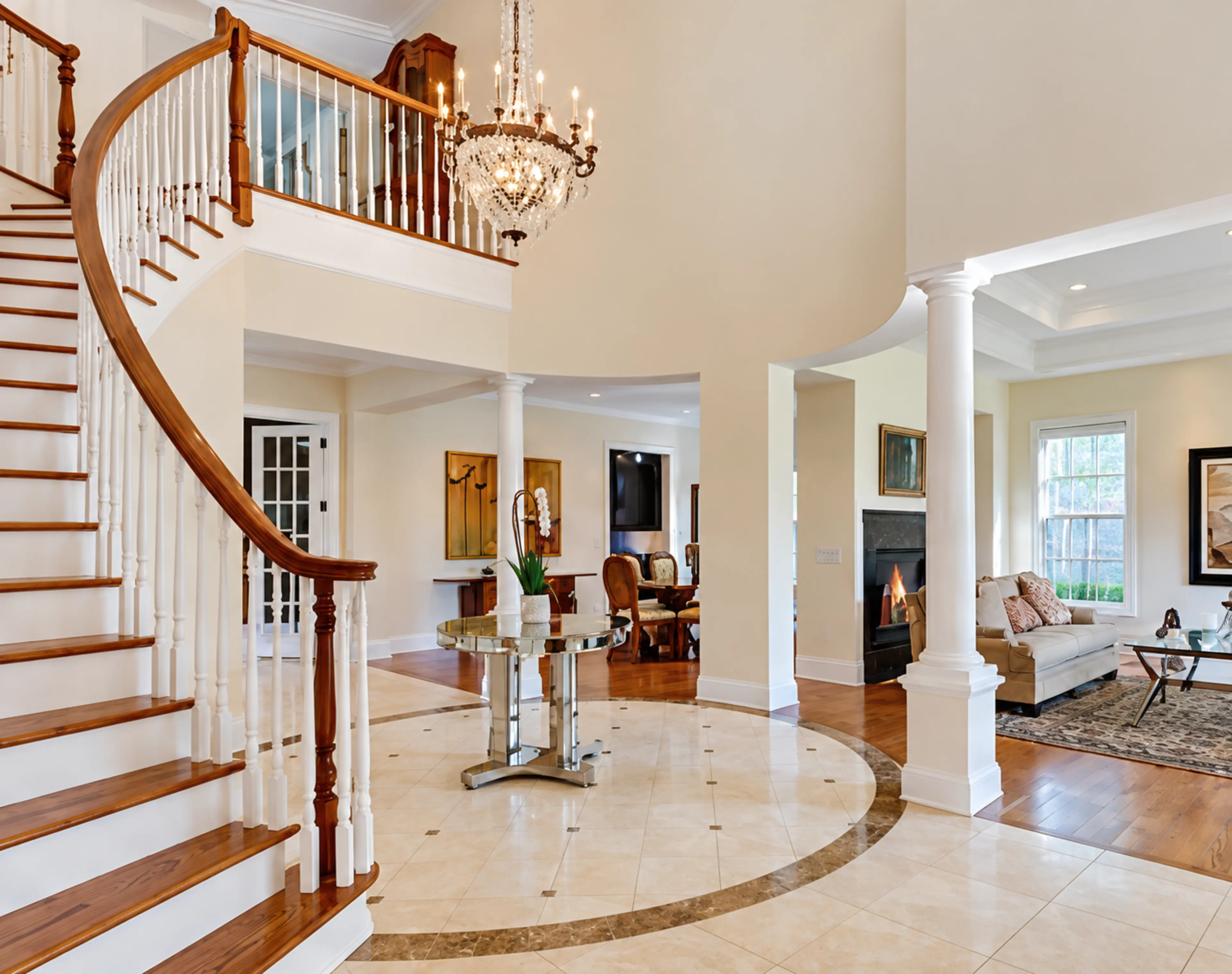 Curved staircase and double-height entry hall with a crystal chandelier