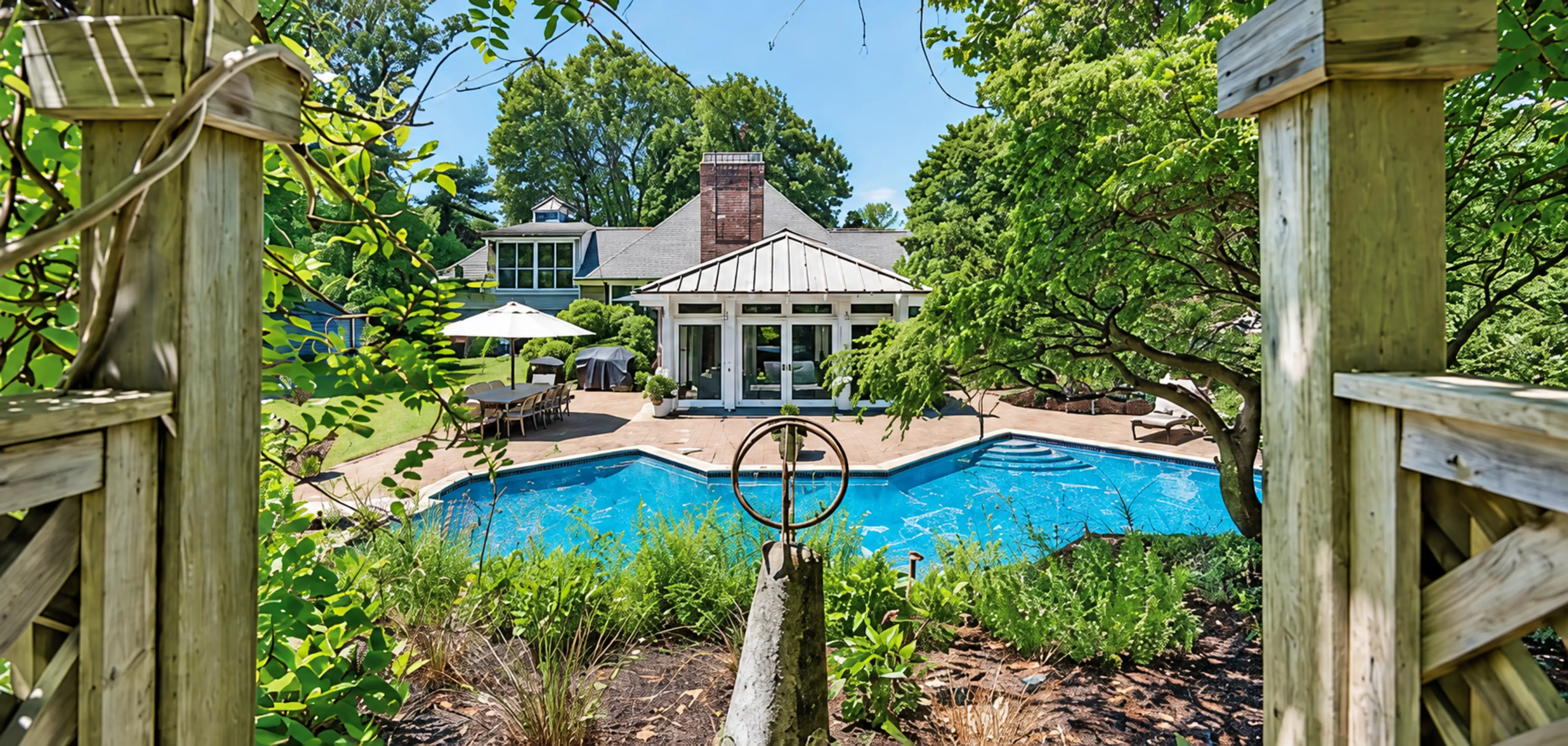 Pool and pool house seen through a timber pergola